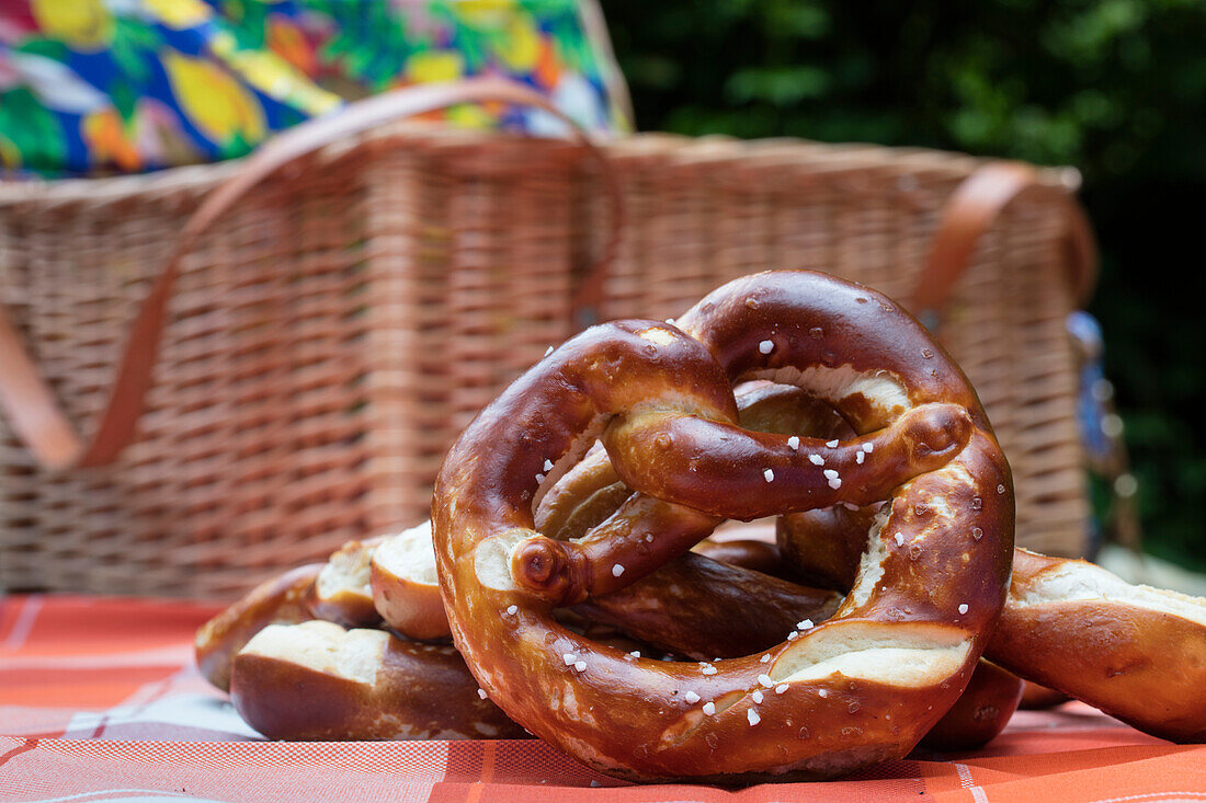 Brezel und Picknickkorb bei Rast während einer Wanderung im Wald, nahe Mespelbrunn, Räuberland, Spessart-Mainland, Bayern, Deutschland