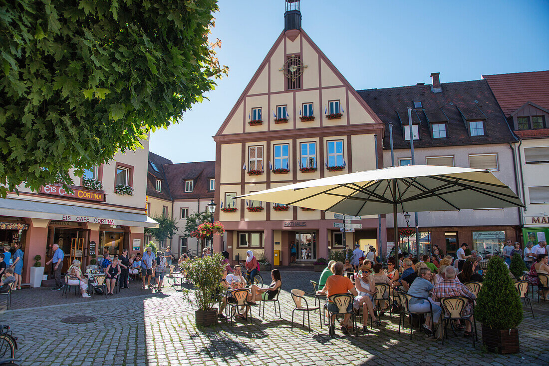 People sit outside cafes and restaurants on Marktplatz market square, Gemuenden am Main, Spessart-Mainland, Bavaria, Germany