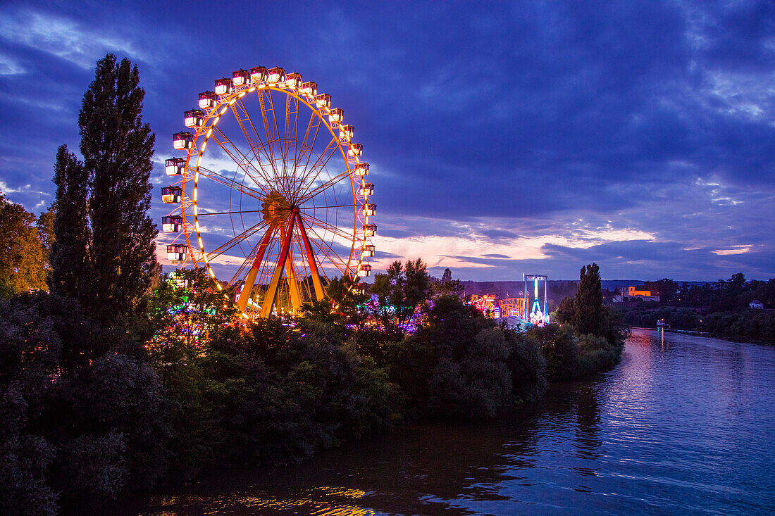 Illuminated ferris wheel at Aschaffenburger Volksfest beerfest and amusement park along Main river at dusk, Aschaffenburg, Spessart-Mainland, Bavaria, Germany