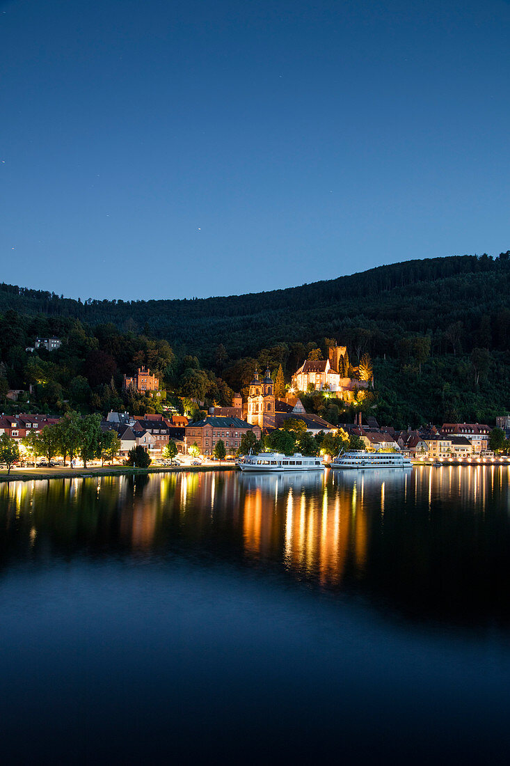 View from Mainbruecke bridge to city and excursion boats on Main river with reflection at dusk, Miltenberg, Spessart-Mainland, Bavaria, Germany