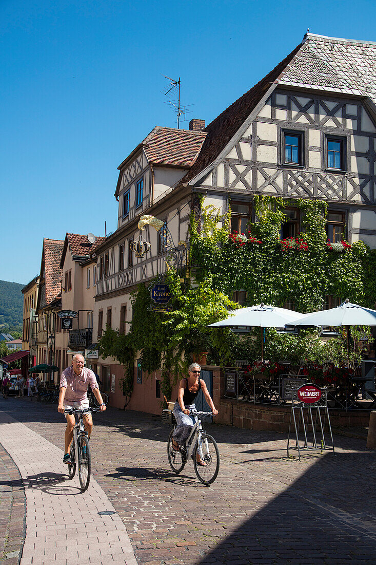 Couple on bicycles in front of half-timbered building in Altstadt old town, Lohr am Main, Spessart-Mainland, Bavaria, Germany