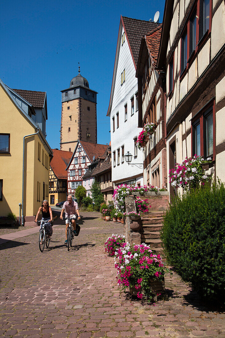 Paar auf Fahrrädern radelt auf Kopfsteinpflaster im Fischerviertel der Altstadt, Lohr am Main, Spessart-Mainland, Bayern, Deutschland