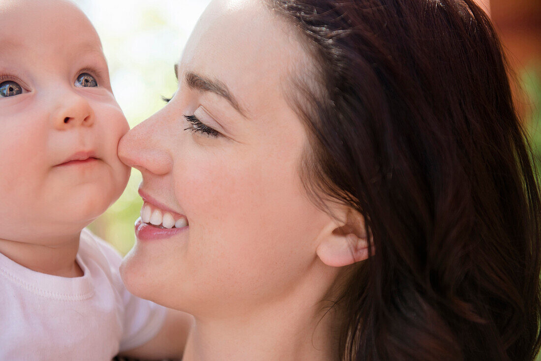 Caucasian mother rubbing nose on cheek of baby son