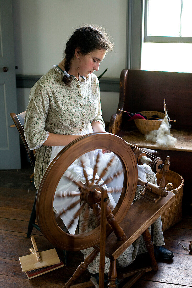 Canada, New Brunswick, Prince William, Kings Landing, living history village reenacting loyalist village from the beginning of the 19th century, young lady in period costume spinning wool
