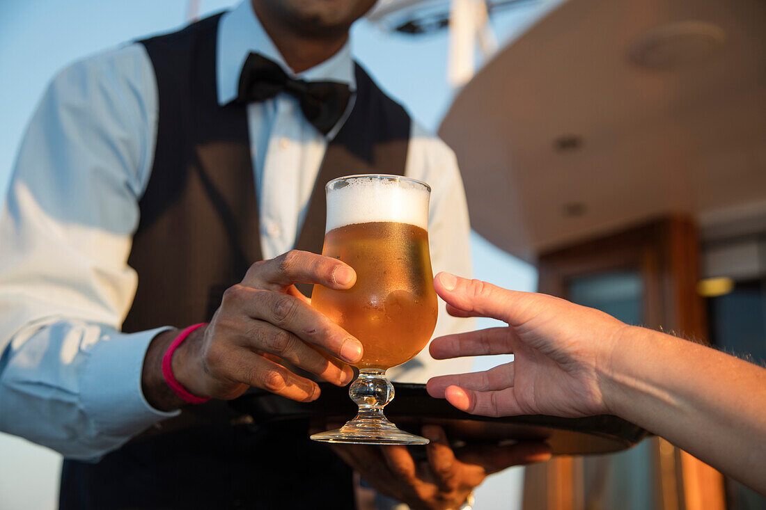 Bar steward an Bord von Motorsegler Kreuzfahrtschiff M/S Panorama (Variety Cruises) serviert einem Passagier ein Glas gekühltes Bier, Adria, nahe Albanien
