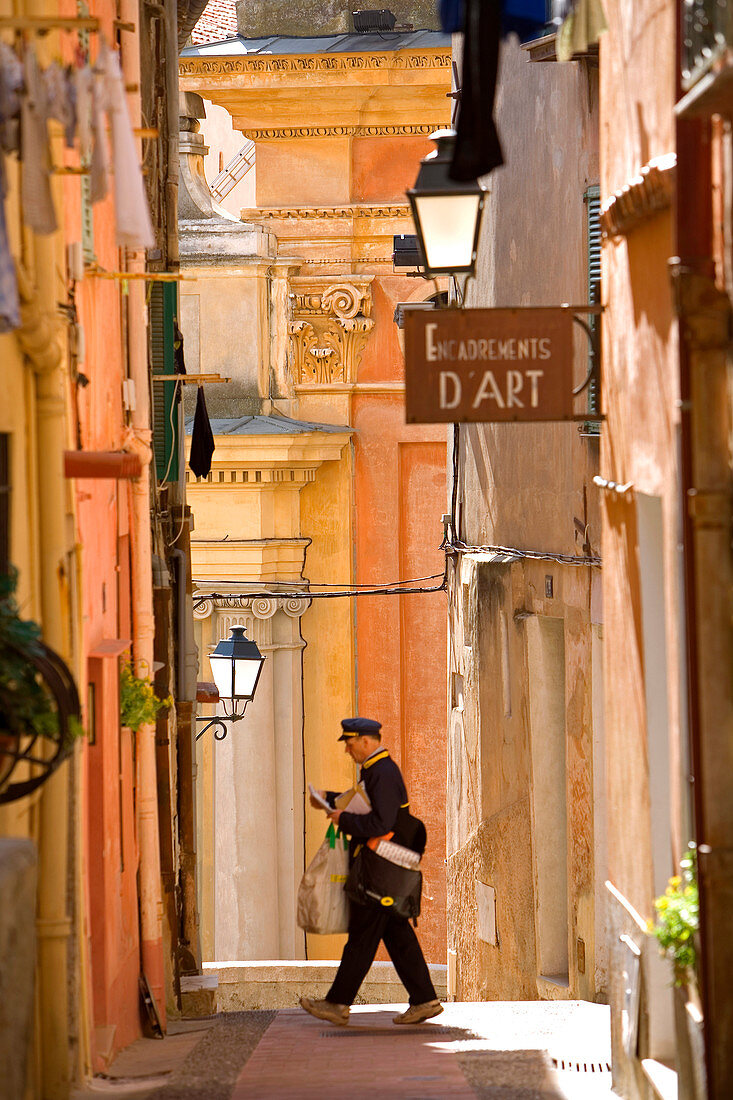 France, Alpes Maritimes, Menton, Rue du Vieux Chateau with the St Michael Basilica in the background, postman