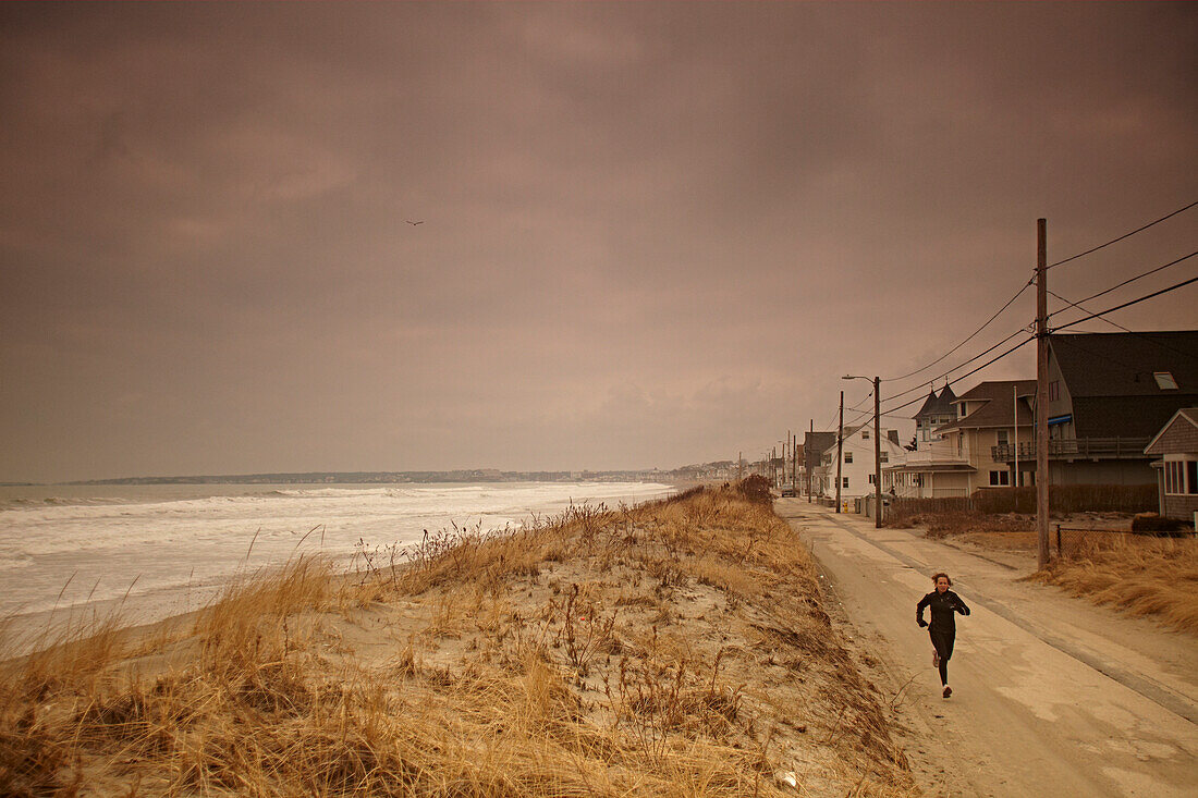 A female athlete on a training run along a road in the beach town of Hull, MA