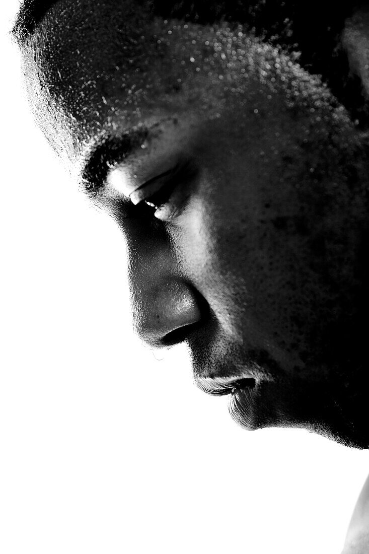 A tight close up of a sweaty african american man against a white backdrop.