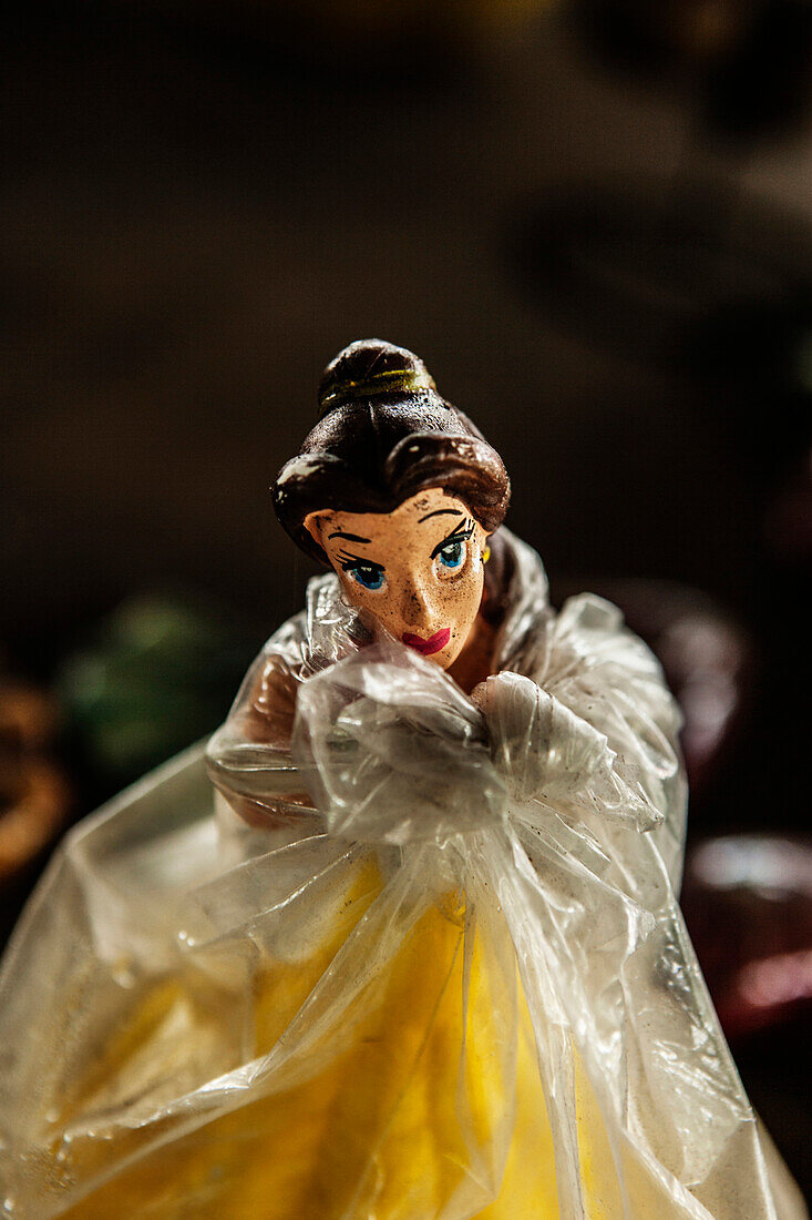 Close up of a female figurine wrapped in clear plastic.