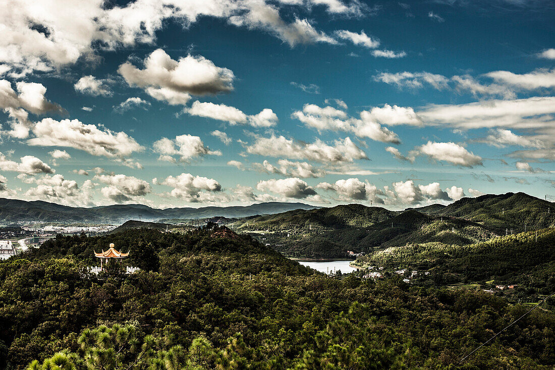 Clouds and blue sky with a Chinese temple in Yunnan Province, China.