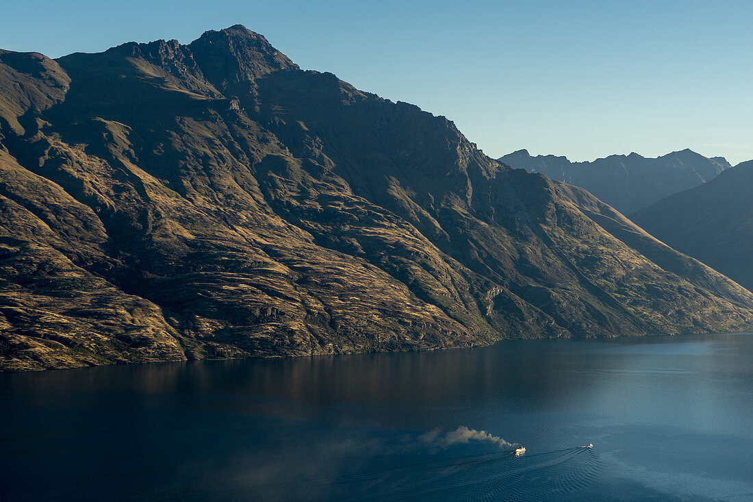 Steamship powers across a dark lake with sharp large mountains, Queenstown, Otago, South Island, New Zealand, Pacific