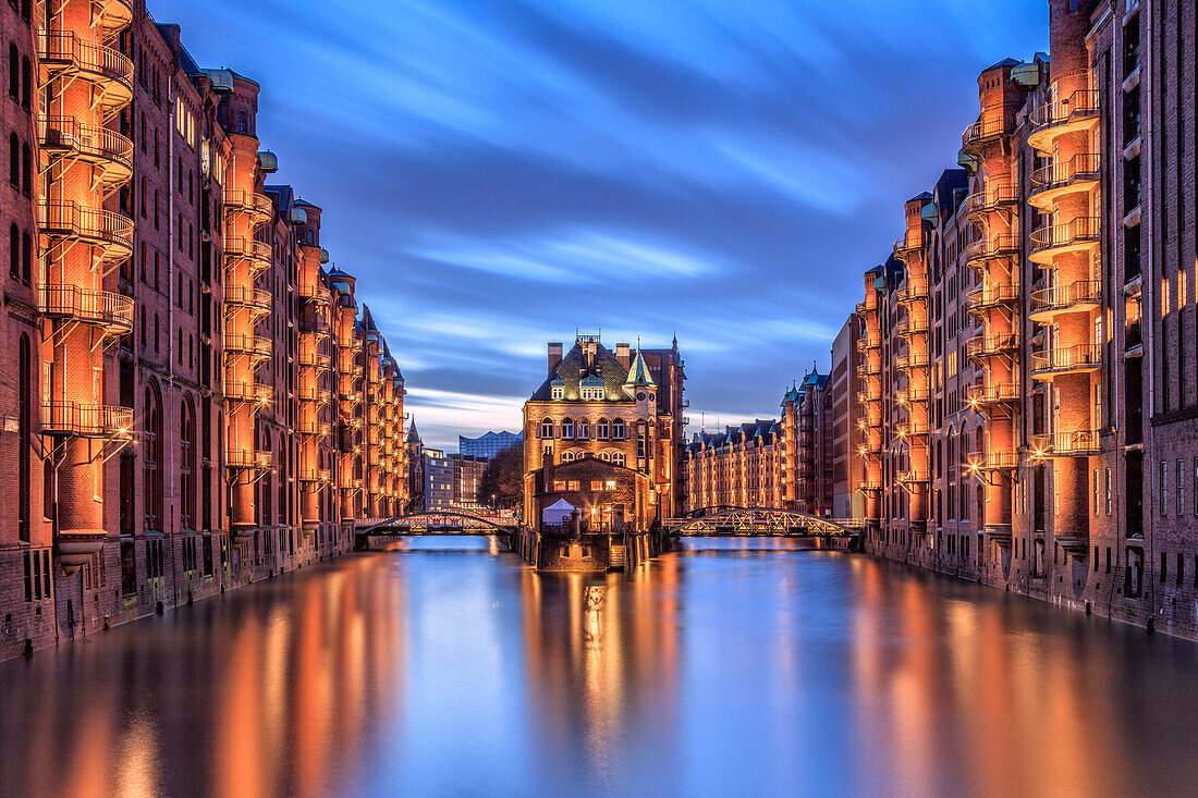 Blue dusk and lights are reflected in Poggenmohlenbrucke with water castle between bridges, Altstadt, Hamburg, Germany, Europe