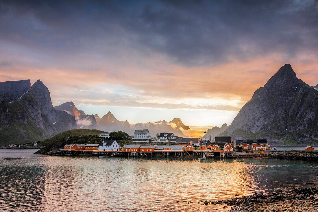 Sunset on the fishing village framed by rocky peaks and sea, Sakrisoya, Nordland county, Lofoten Islands, Arctic, Northern Norway, Scandinavia Europe