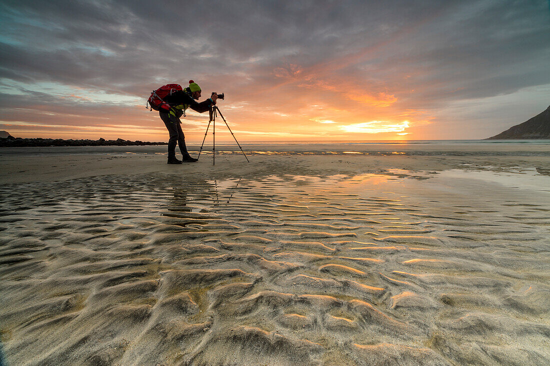 Midnight sun frames photographer in action on Skagsanden beach, Ramberg, Nordland county, Lofoten Islands, Arctic, Northern Norway, Scandinavia, Europe