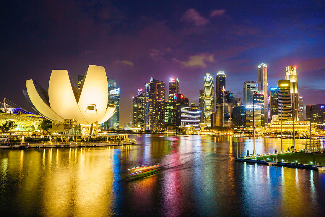 The lotus flower shaped ArtScience Museum overlooking Marina Bay with the city skyline beyond illuminated at night, Singapore, Southeast Asia, Asia
