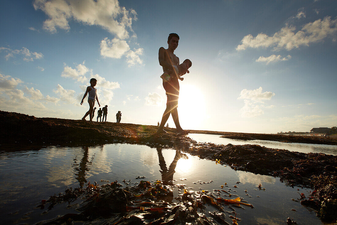 Mann mit Kleinkind am Strand von Canggu bei Ebbe, Bali, Indonesien, Asien