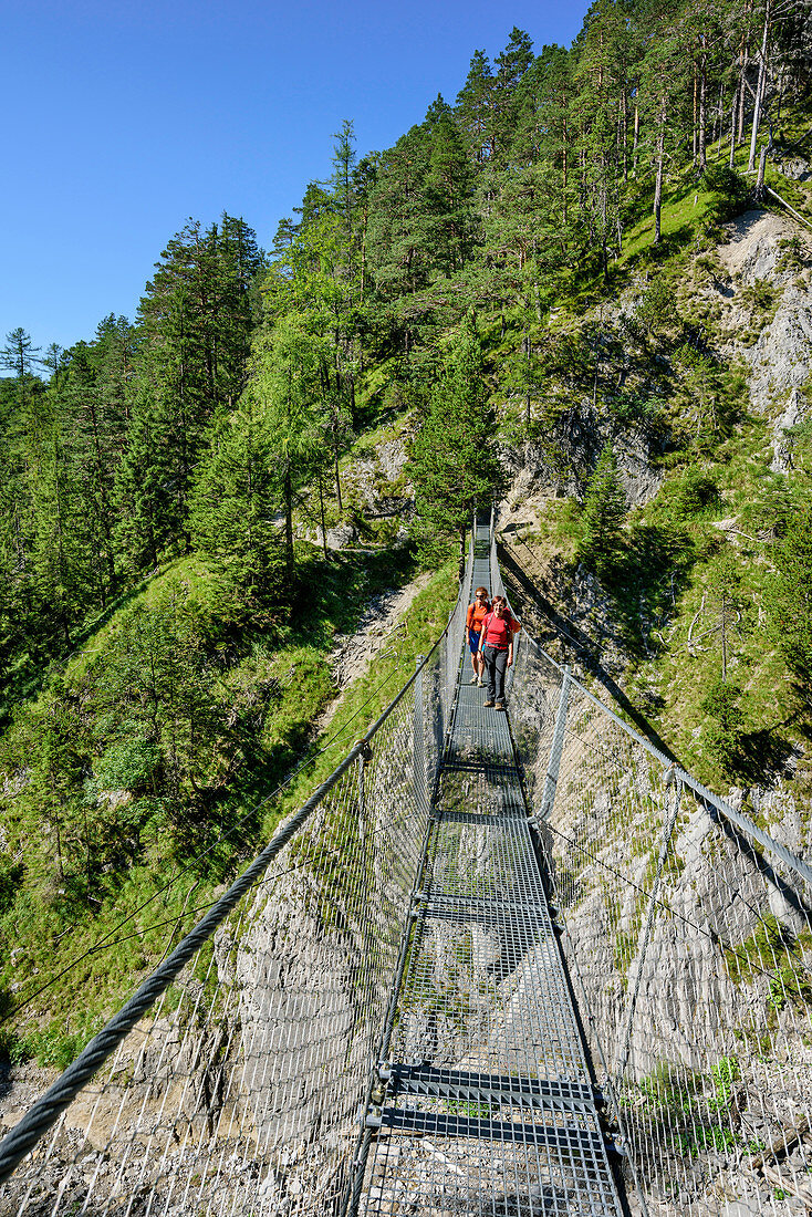Two women walking on suspension bridge near hut Brunnsteinhuette, hut Brunnsteinhuette, Karwendel range, Upper Bavaria, Bavaria, Germany