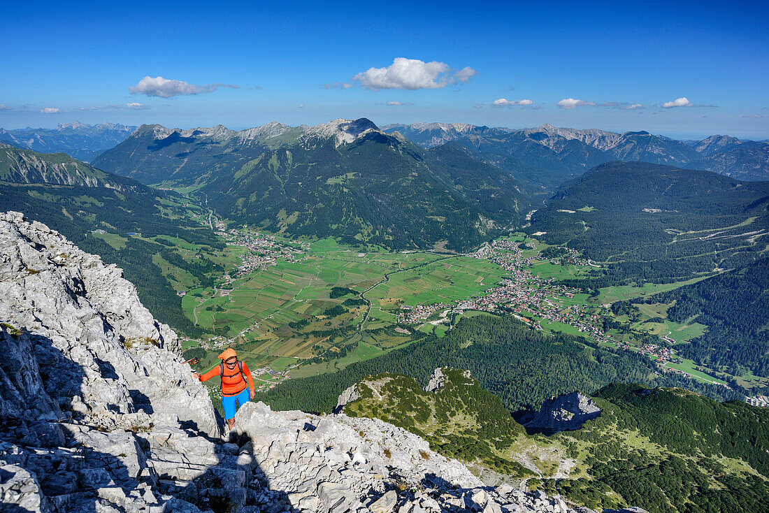 Woman hiking towards Ehrwalder Sonnenspitze, Lermoos, Ehrwald and Ammergau Alps in background, Ehrwalder Sonnenspitze, Mieming range, Tyrol, Austria