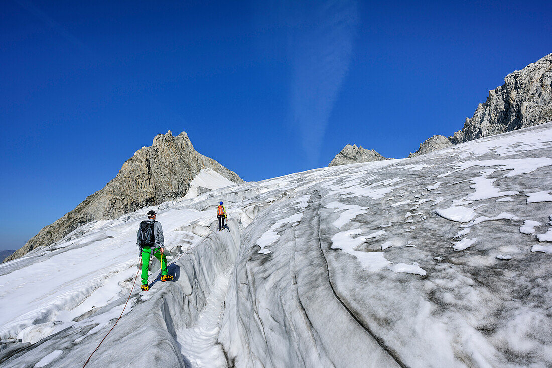 Mann und Frau steigen über spaltigen Gletscher auf, Kuchelmooskopf im Hintergrund, Kuchelmoosferner, Zillergrund, Reichenspitzgruppe, Zillertaler Alpen, Tirol, Österreich