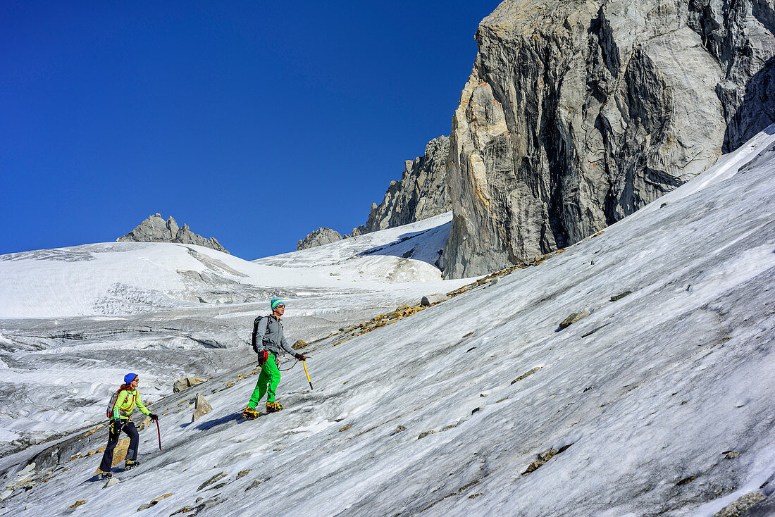 Man and woman ascending on glacier Kuchelmoosferner, Zillergrund, Reichenspitze group, Zillertal Alps, Tyrol, Austria