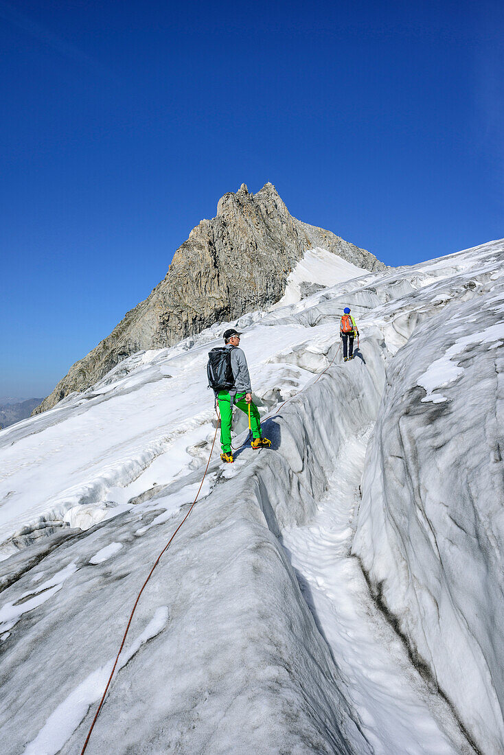 Mann und Frau steigen über spaltigen Gletscher auf, Kuchelmooskopf im Hintergrund, Kuchelmoosferner, Zillergrund, Reichenspitzgruppe, Zillertaler Alpen, Tirol, Österreich