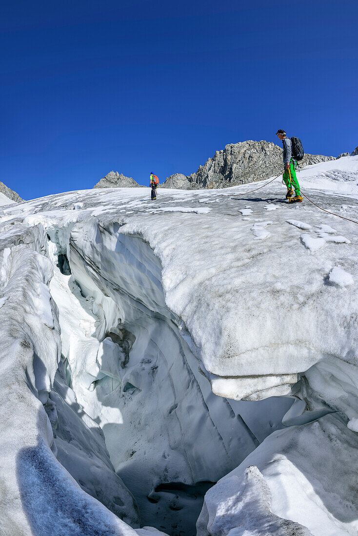 Mann und Frau steigen über spaltigen Gletscher auf, Kuchelmoosferner, Zillergrund, Reichenspitzgruppe, Zillertaler Alpen, Tirol, Österreich