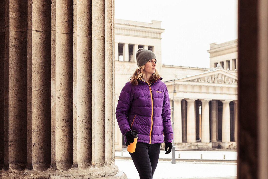 Young woman with coffee mug on snowy Königs Plaza in Munich, Bavaria, Germany