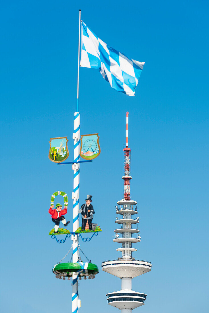 Der Maibaum eines bayrischen Fahrgeschäftes auf dem Hamburger Jahrmarkt Dom mit dem Fernsehturm, Hamburg, Deutschland
