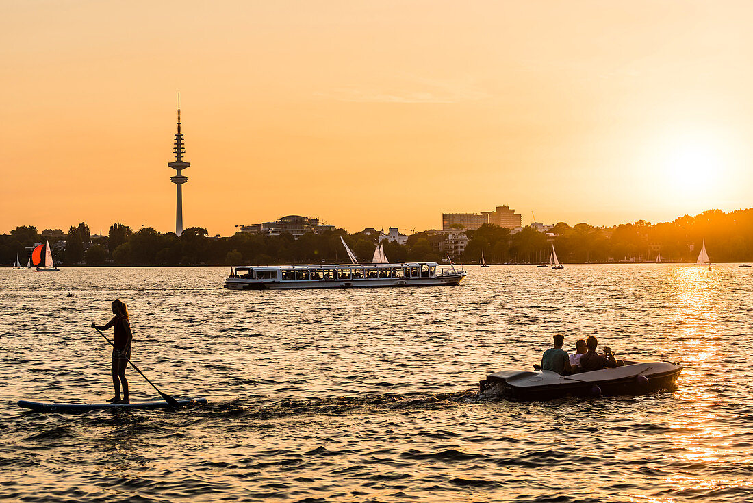 Boats and water sports enthusiasts on the lake Aussenalster at sunset, Hamburg, Germany