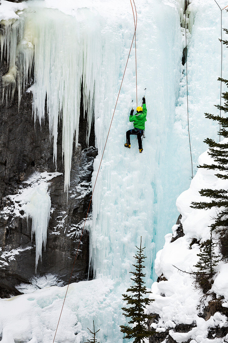 Male ice climber on frozen ice falls, Alberta, Canada
