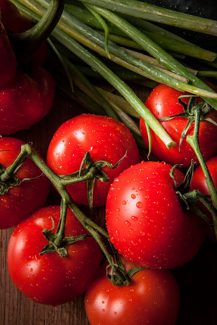 Bright red, ripe tomatoes with water droplets and green onions