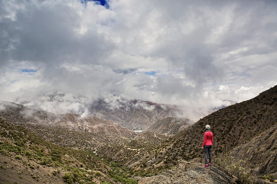 Hiker standing at the top of a mountain looking out, just north of Tupiza, Bolivia