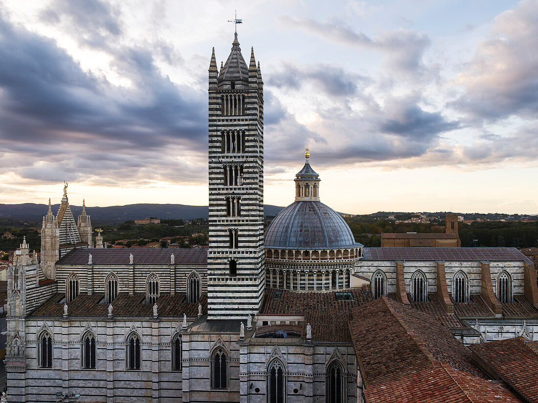 Striped facade of a tower and dome roof of Siena Cathedral, Siena, Italy