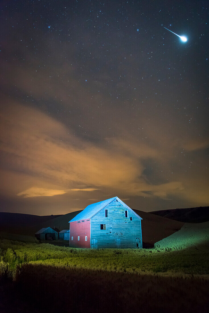 Stars and constellations above a farmhouse and barn in a wheat field at night, Palouse, Washington, United States of America