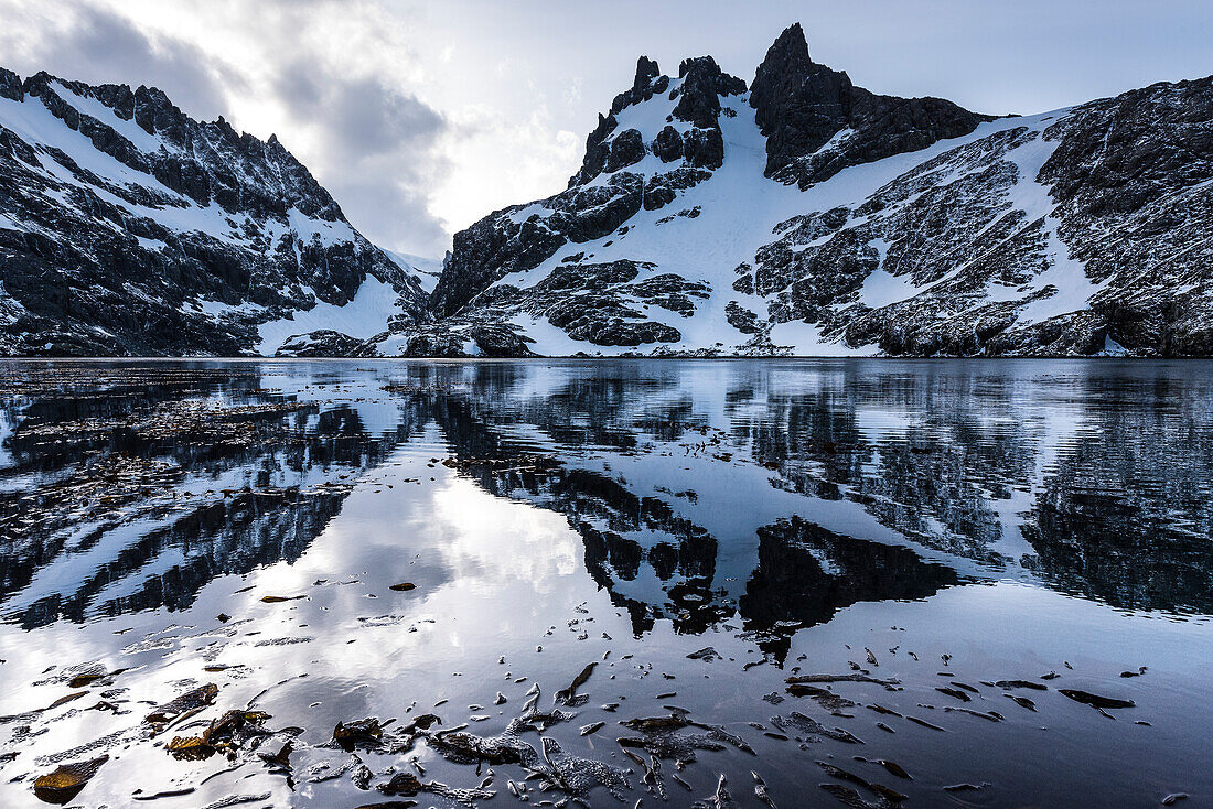 Reflections of snow covered rugged mountains in water, Antarctica