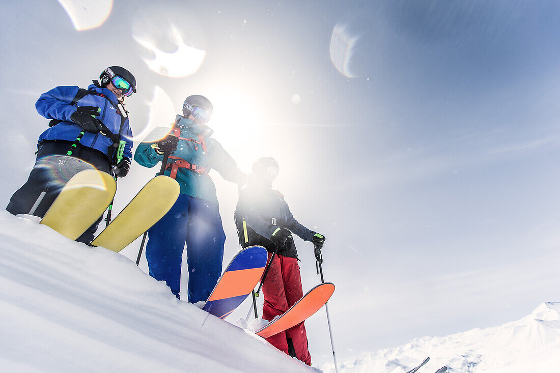 Drei junge Skifahrer stehen auf der Kante einer Schneewehe in den Bergen, Gudauri, Mzcheta-Mtianeti, Georgien
