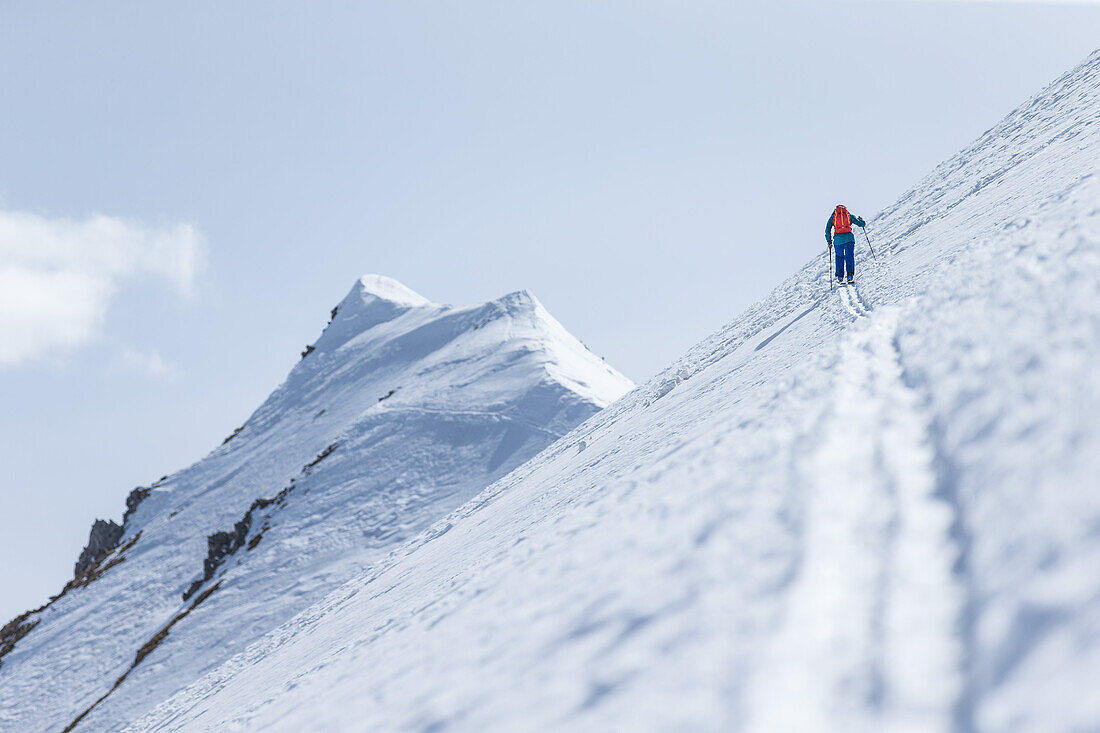Young male skier hikiing up through the deep powder snow to a mountain peak, Gudauri, Mtskheta-Mtianeti, Georgia