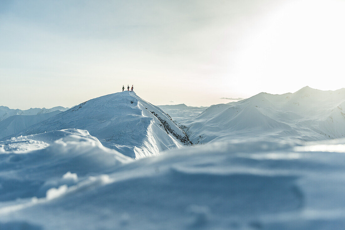 Drei junge Skifahrer laufen durch den Tiefschnee auf den Gipfel eines Berges, Gudauri, Mzcheta-Mtianeti, Georgien