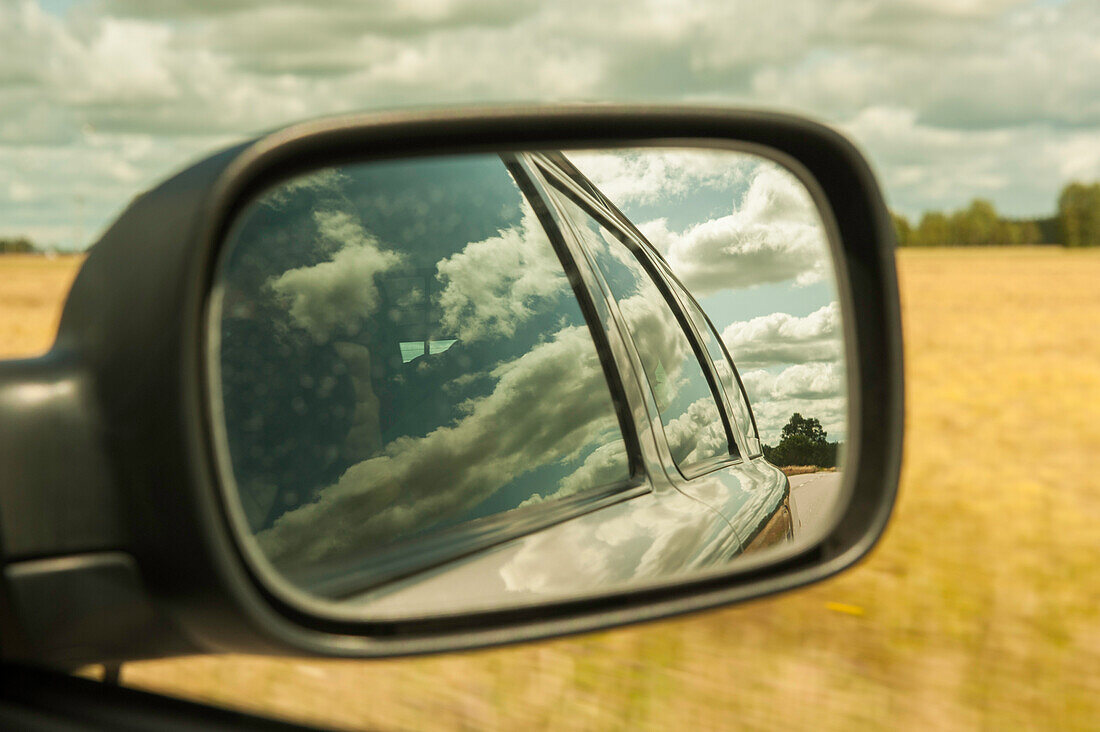view into the car wing mirror, summer landscape, field, clouds, Smaland, Sweden