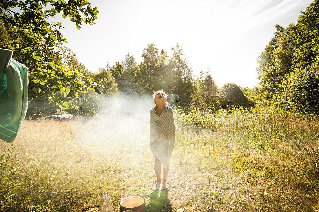Kind nach der morgendlichen Dusche auf einer Wiese im Sonnenlicht, Halland, Sweden