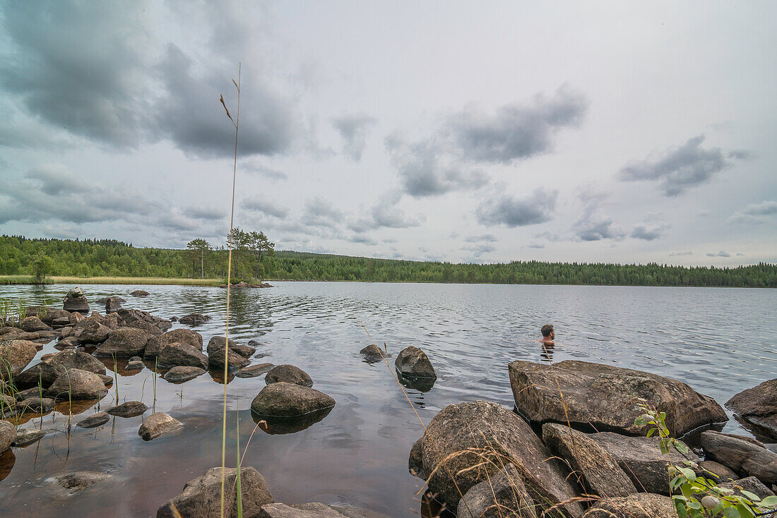 Mann badet an einem kühlen Sommertag im See, Värmland, Schweden