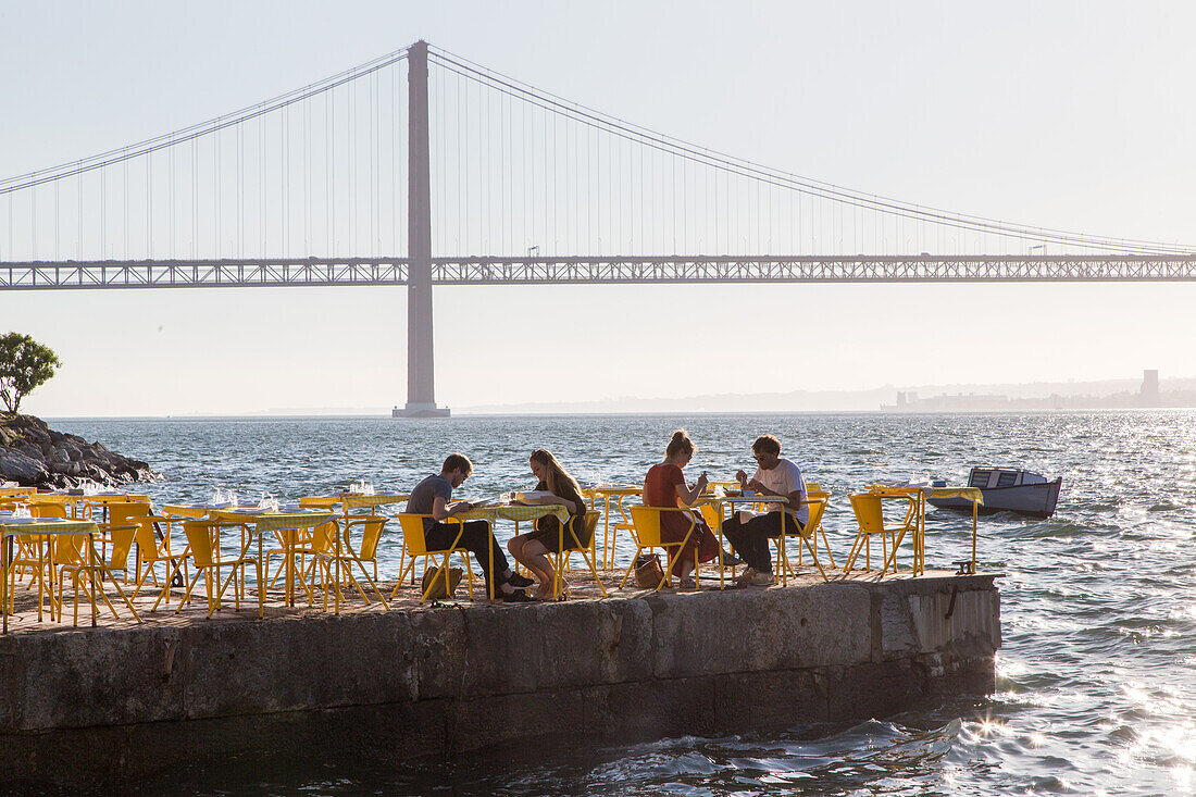 riverfront restaurant Ponto Final, view from south bank of River Tagus,and the 25th April Bridge, Cacilhas, Almada, Lisbon, Portugal