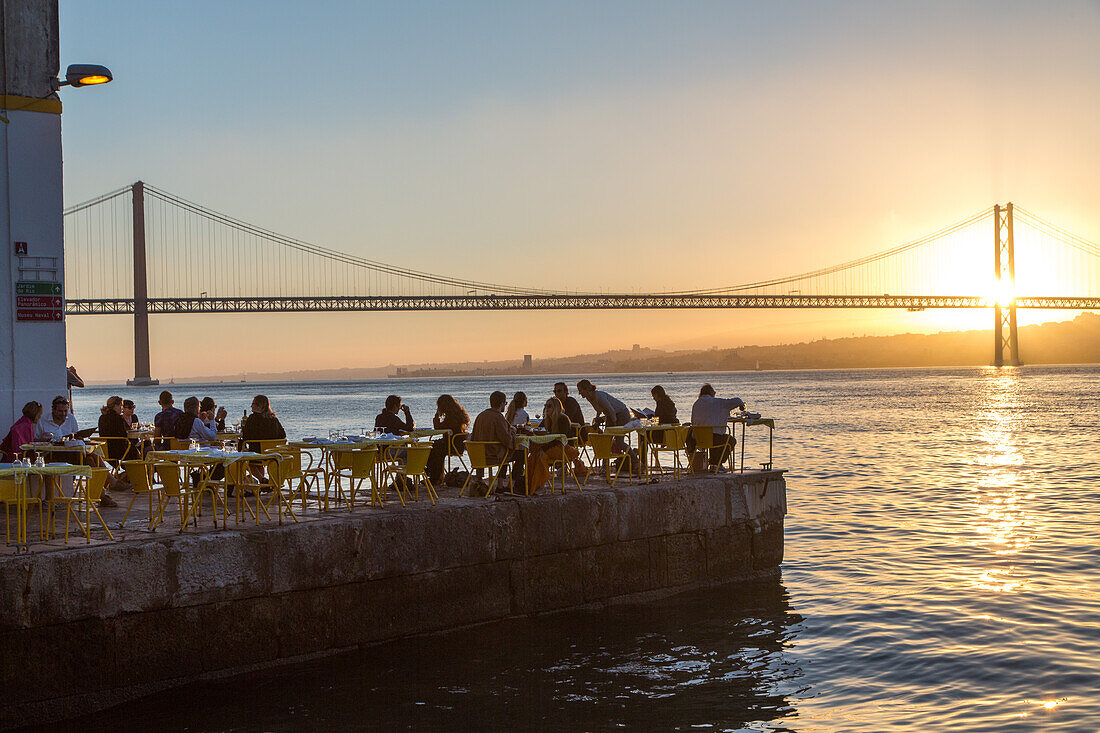 sunset on riverfront restaurant Ponto Final, view from south bank of River Tagus,and the 25th April Bridge, Cacilhas, Almada, Lisbon, Portugal