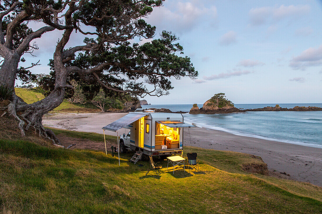idyllic camping location, shady old Pohutukawa tree, empty beach, 4WD Campervan, Campsite, Elliot Bay, North Island, New Zealand