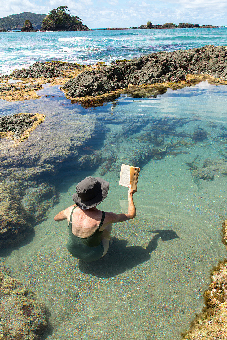 Entspannung, Frau, Buch lesen im natürlichen Gezeitenbecken, Abkühlung, Pool, Elliot Bay, Nordinsel Neuseeland