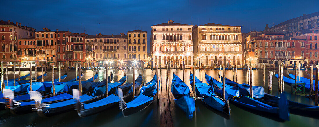 Panorama overlooking the Grand Canal with the illuminated facades of Palazzo Ca 'Loredan and Palazzo Ca' Farsetti (from left) in blue night and gondolas in the foreground, San Marco, Venice, Veneto, Italy