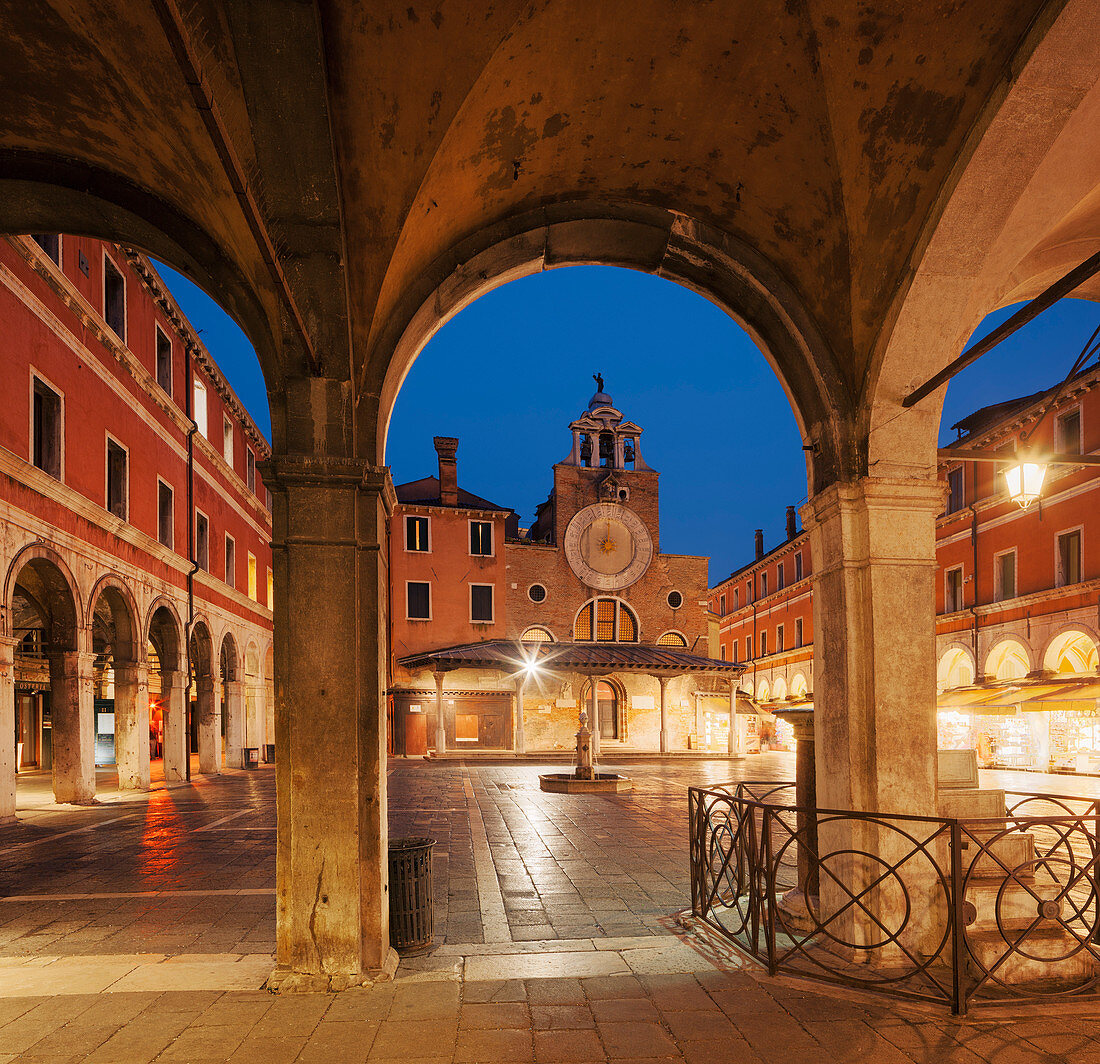 Overlooking the Campo San Giacomo di Rialto with archs, booths and the illuminated facade of the church Chiesa di San Giacomo di Rialto in blue at night, San Polo, Venice, Veneto, Italy