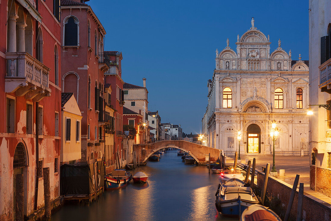 Blick auf den Kanal Rio dei Mendicanti mit beleuchteter Scuola Grande di San Marco die historische Fassade des Krankenhaus Ospedale und Booten im Blau der Nacht, Sestiere Castello, Venedig, Venezien, Italien