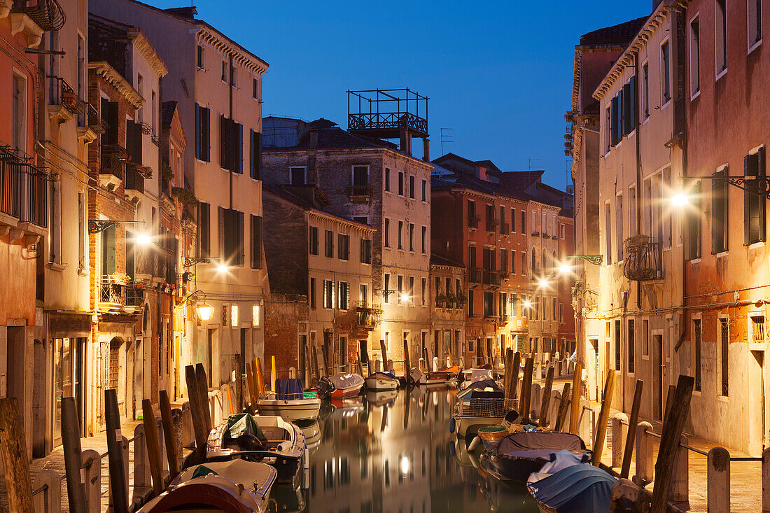 Illuminated facades and boats on the canal Rio Ognissanti in blue night, Dorsoduro, Venice, Veneto, Italy