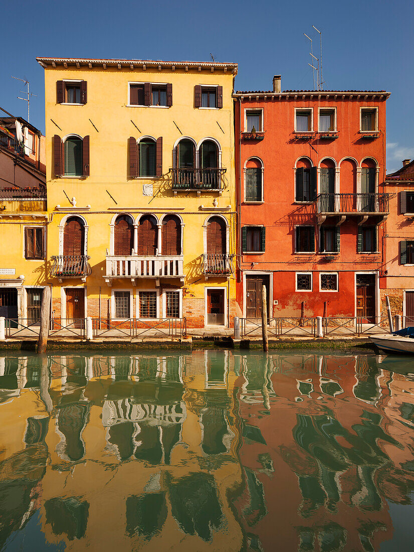 Bunte Häuser mit Spiegelung im Kanal Rio di Santa Fosca in der Morgensonne und blauem Himmel, Cannaregio, Venedig, Venezien, Italien